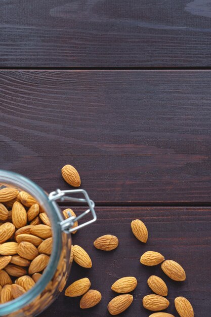 Mandorle in barattolo di vetro sul tavolo di legno scuro. Alimenti proteici biologici per la salute. Spazio di copia con messa a fuoco selettiva