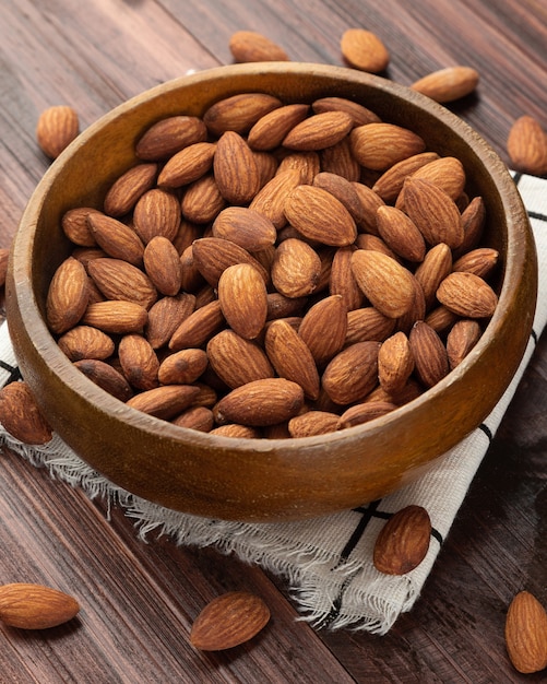 Mandorle in ciotola di legno sul tavolo, spuntino sano, cibo vegetariano.