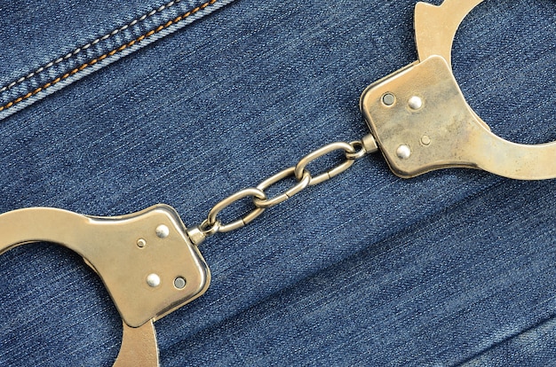 Manette d&#39;acciaio della polizia che si trovano sul fondo blu scuro delle jeans