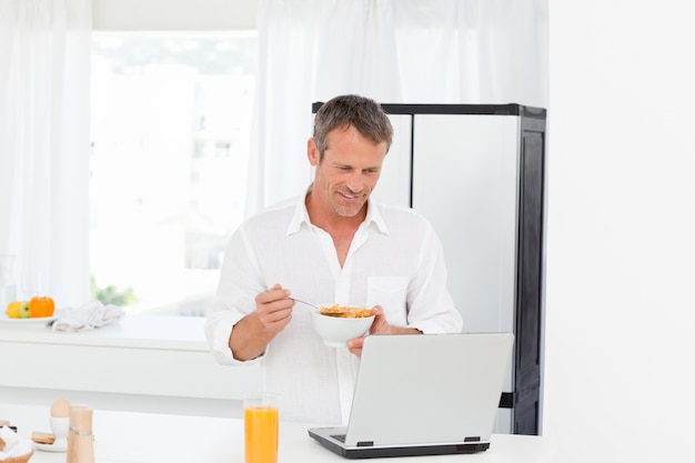 Mangia cereali mentre sta lavorando sul suo computer portatile