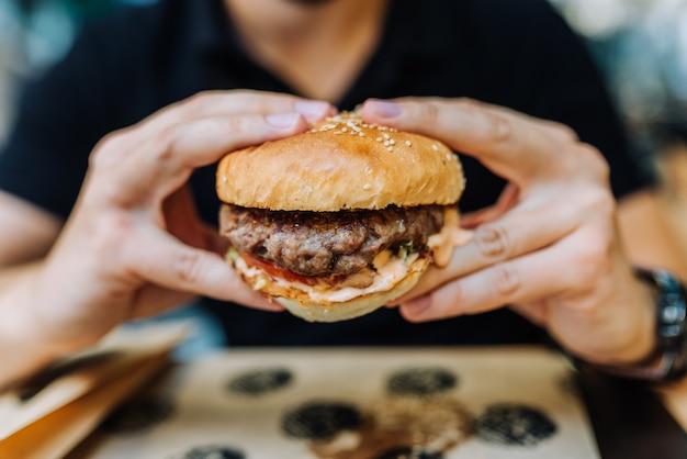 Mangiare hamburger gustoso. Avvicinamento.