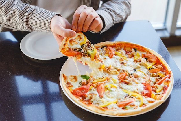 Mangiare la pizza a casa. Consegna deliziosa della pizza. L'uomo caucasico prende il pezzo di deliziosa pizza italiana con mozzarella a casa o in bar, ristorante. Pizza Fast Food.