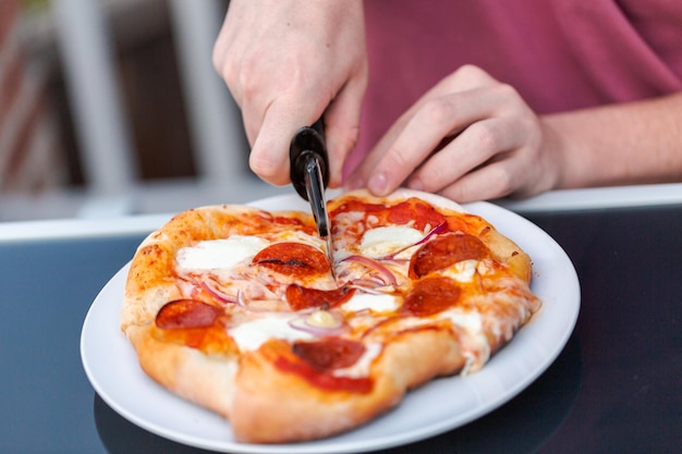 Mangiare la pizza cotta sul grill a gas all'aperto.