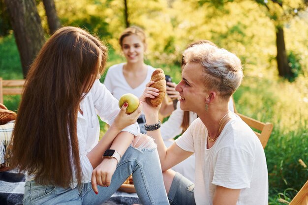 Mangiare mele e biscotti Un gruppo di giovani trascorre una vacanza all'aria aperta nella foresta Concezione del fine settimana e dell'amicizia