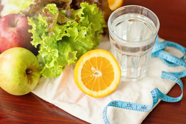 Mangiare sano, bevande, misurazione del nastro blu, dieta, disintossicazione e concetto di persone - chiudere l'acqua di frutta in vetro