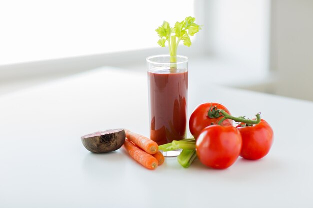 mangiare sano, cibo biologico e concetto di dieta - primo piano di un bicchiere di succo fresco e verdure sul tavolo