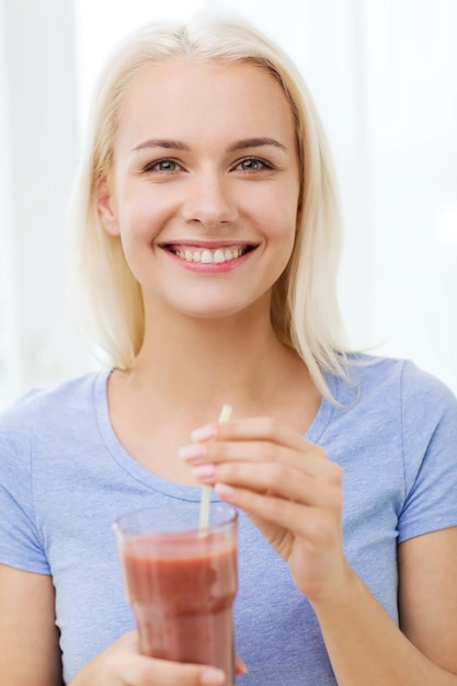 mangiare sano, cibo vegetariano, dieta e concetto di persone - donna sorridente che beve succo o frullato dal vetro a casa