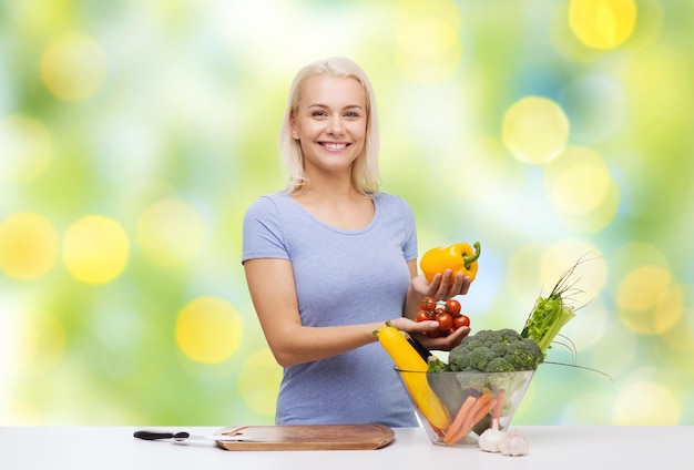 mangiare sano, cucinare, cibo vegetariano, dieta e concetto di persone - giovane donna sorridente con una ciotola di verdure su sfondo di luci verdi