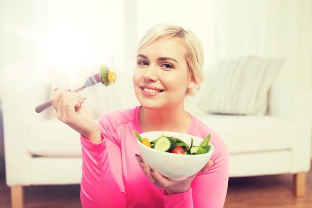 mangiare sano, dieta e concetto di persone - giovane donna sorridente che mangia insalata di verdure a casa
