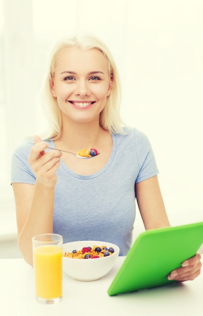 mangiare sano, dieta e concetto di persone - giovane donna sorridente con computer tablet pc mangiare colazione a casa