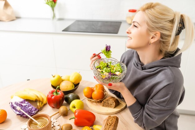 mangiare sano, dieta e concetto di persone - primo piano di giovane donna che mangia insalata di verdure a casa.