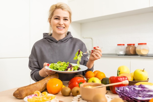 mangiare sano, dieta e concetto di persone - primo piano di giovane donna che mangia insalata di verdure a casa.