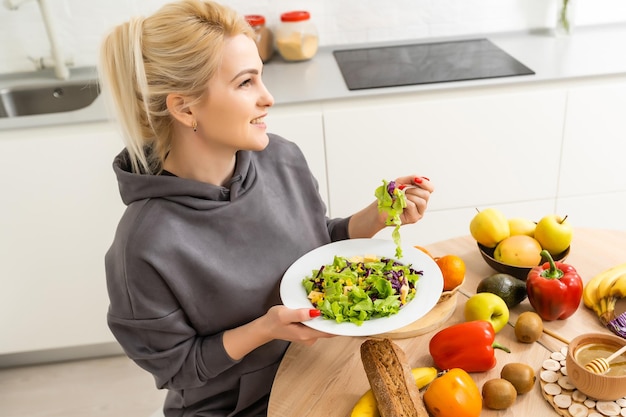 mangiare sano, dieta e concetto di persone - primo piano di giovane donna che mangia insalata di verdure a casa.