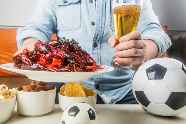 Mangiare snack e birra e guardare il calcio dal vivo