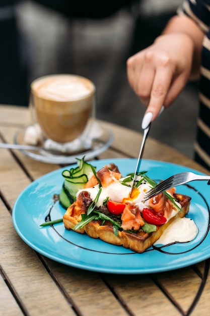 Mangiare waffle toast con uovo in camicia e salmone con caffè