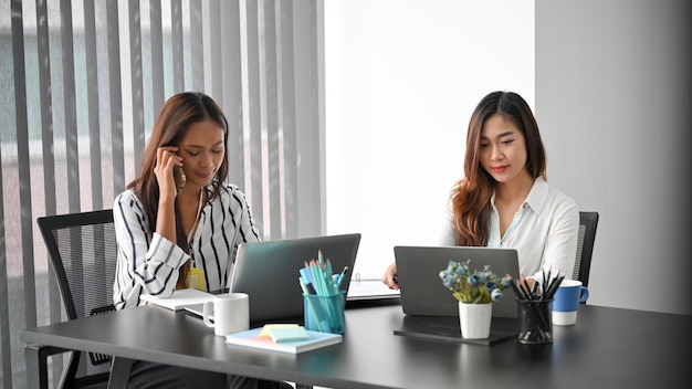 Mangiatoia femminile che parla con potenziali partner commerciali mentre il suo collega lavora al laptop