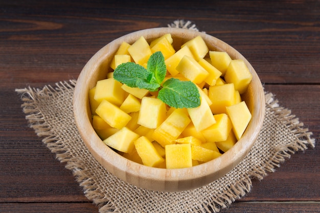 Mango della frutta tropicale in un piatto su un fondo di legno, intero o affettato.