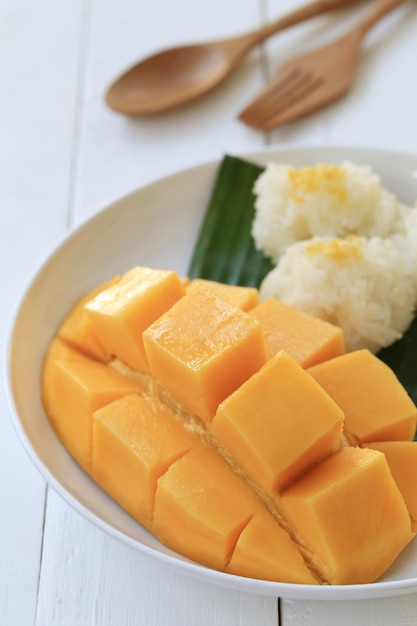 Mango e riso appiccicoso in piatto bianco sul pavimento di legno bianco