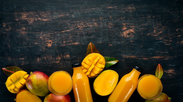 Mango e succo fresco su uno sfondo di legno nero Frutti tropicali Vista dall'alto spazio libero per il testo