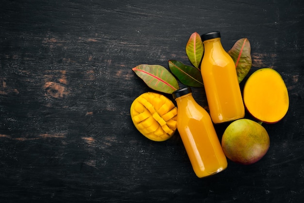 Mango e succo fresco su uno sfondo di legno nero Frutti tropicali Vista dall'alto spazio libero per il testo