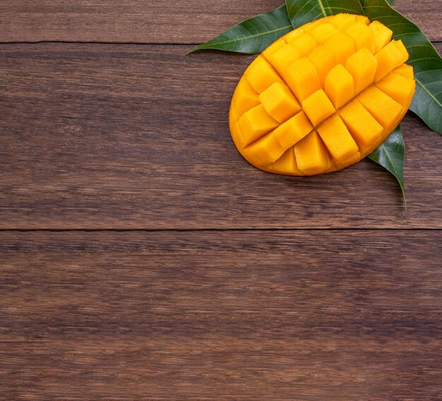 Mango fresco bella frutta tritata con foglie verdi su sfondo di legno scuro Concetto di design di frutta tropicale Posa piatta Vista dall'alto Spazio di copia