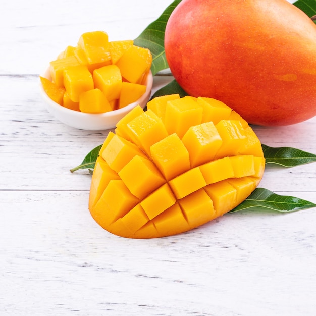 Mango fresco, bella frutta tritata con foglie verdi su sfondo luminoso tavolo in legno. Concetto di design di frutta tropicale, primo piano, copia dello spazio.