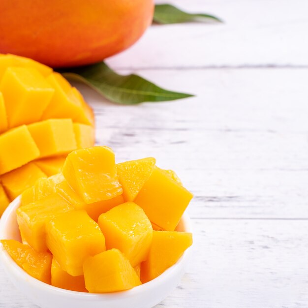 Mango fresco, bella frutta tritata con foglie verdi su sfondo luminoso tavolo in legno. Concetto di design di frutta tropicale, primo piano, copia dello spazio.