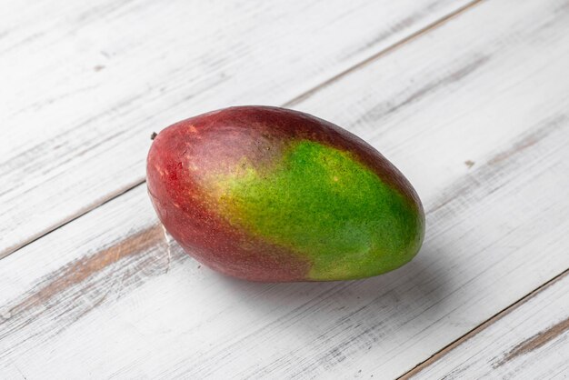 Mango intero su fondo di legno bianco Frutto acerbo