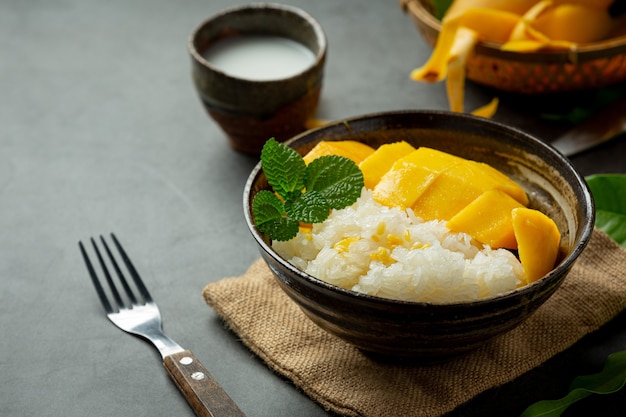 Mango maturo fresco e riso appiccicoso con latte di cocco sulla superficie scura