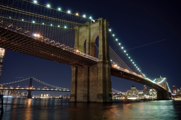 Manhattan Bridge e Brooklyn Skyline con bel riflesso sfocato nel fiume di notte