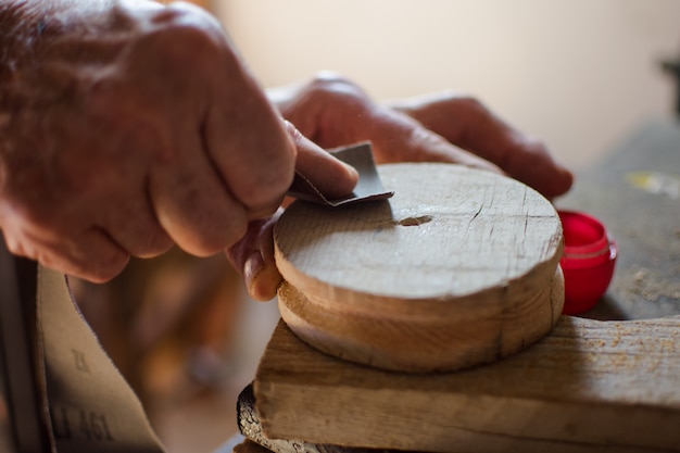 Mani anziane che sfregano il legno dalla carta vetrata