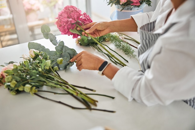 Mani attente di un fiorista che sistemano i fiori in una composizione