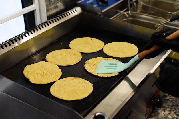 Mani che arrostiscono tortillas per tacos in un ristorante messicano