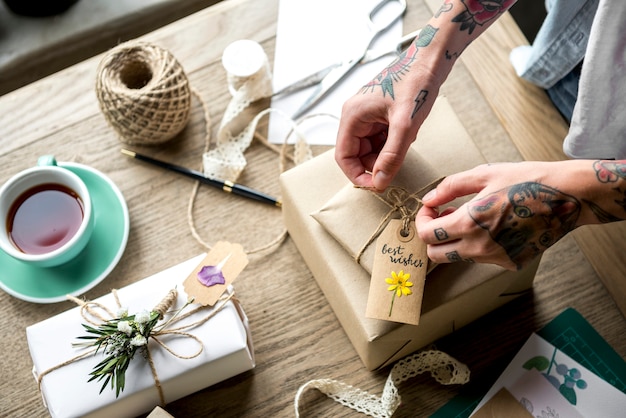 Mani che avvolgono scatola regalo con decorazione floreale