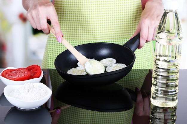 Mani che cucinano i zucchine in padella in cucina