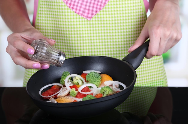 Mani che cucinano il ragù di verdure in padella in cucina