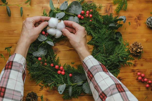 Mani che decorano la ghirlanda di Natale fai-da-te con un batuffolo di cotone