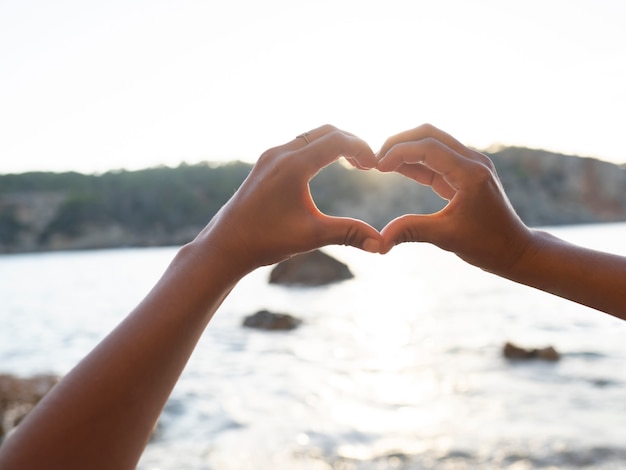 Mani che formano un cuore sulla spiaggia