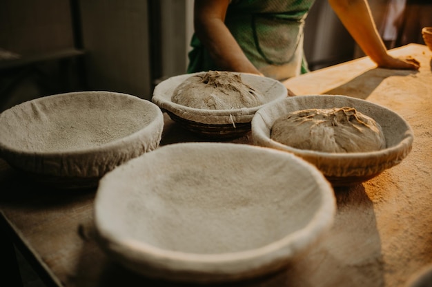 Mani che impastano la pasta del pane su un tagliere