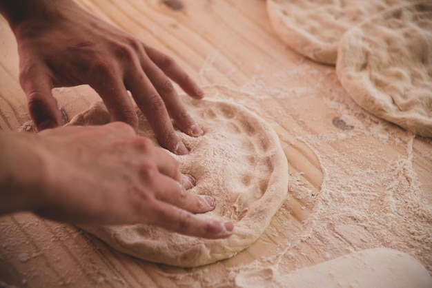 mani che impastano una pizza, panetteria