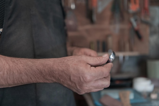 Mani che intagliano un cucchiaio di legno, lavorando con lo scalpello da vicino. Officina in legno. Processo di fabbricazione del cucchiaio di legno. Foto di alta qualità