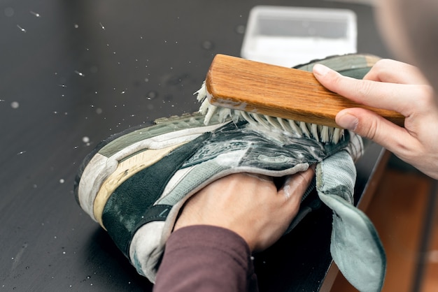 Mani che lavano le scarpe da ginnastica con un pennello