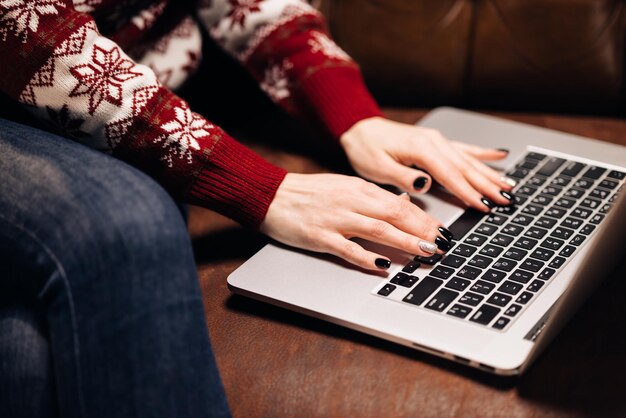 Mani che lavorano su laptop con ornamenti natalizi ragazza che utilizza laptop seduta sul divano entro natale