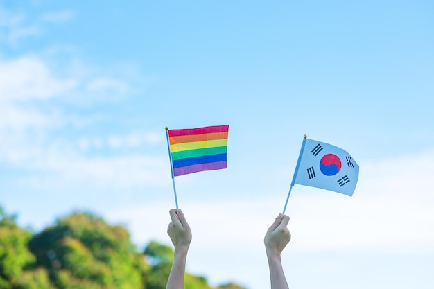 Mani che mostrano LGBTQ bandiera arcobaleno e Corea sullo sfondo della natura supporto lesbiche gay bisessuali transgender e comunità queer e concetto di mese di orgoglio