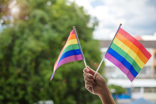 Mani che mostrano LGBTQ bandiera arcobaleno su sfondo verde natura supporto lesbiche gay bisessuali transgender e comunità queer e concetto di mese di orgoglio