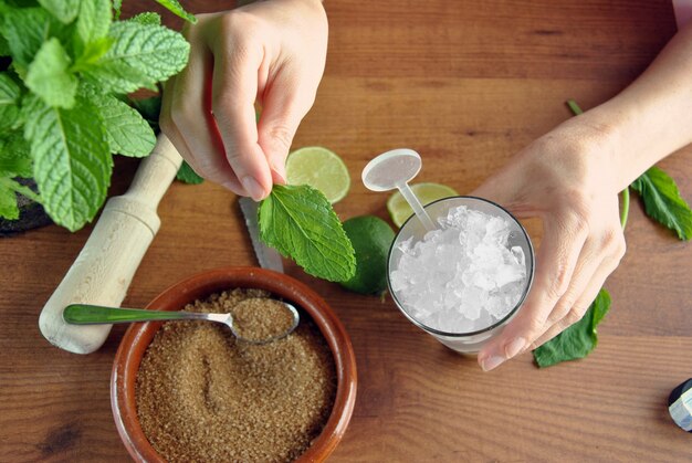 Mani che preparano cocktail mojito con lime e menta