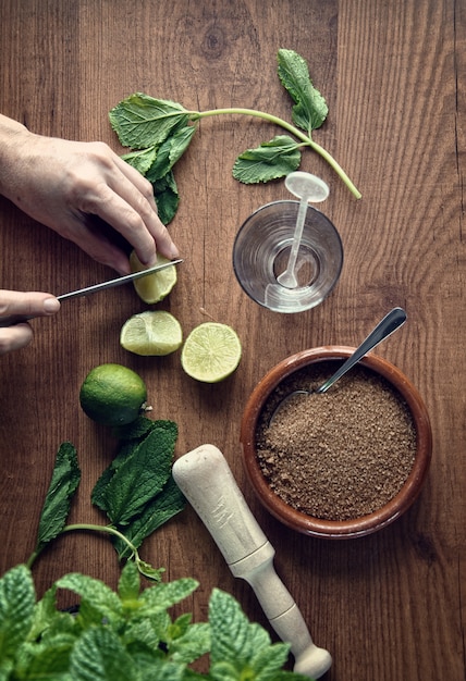 Mani che preparano cocktail mojito con lime e menta