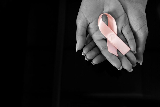 Mani che presentano un nastro rosa per la consapevolezza del cancro al seno