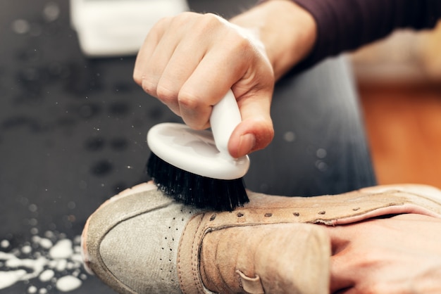 Mani che puliscono le sneakers in camoscio