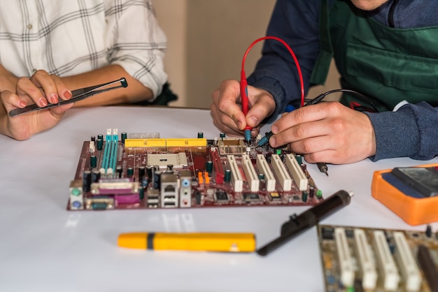 Mani che riparano la scheda madre del computer mediante saldatura